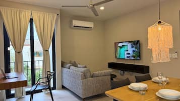 A modern living room with a sofa, dining table, and TV.