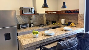 A modern kitchen with granite countertops, stainless steel appliances, and pendant lighting. - Rooms M (Santa María Huatulco)