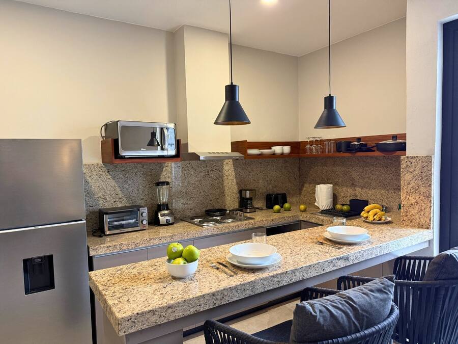 A modern kitchen with granite countertops, stainless steel appliances, and pendant lighting.