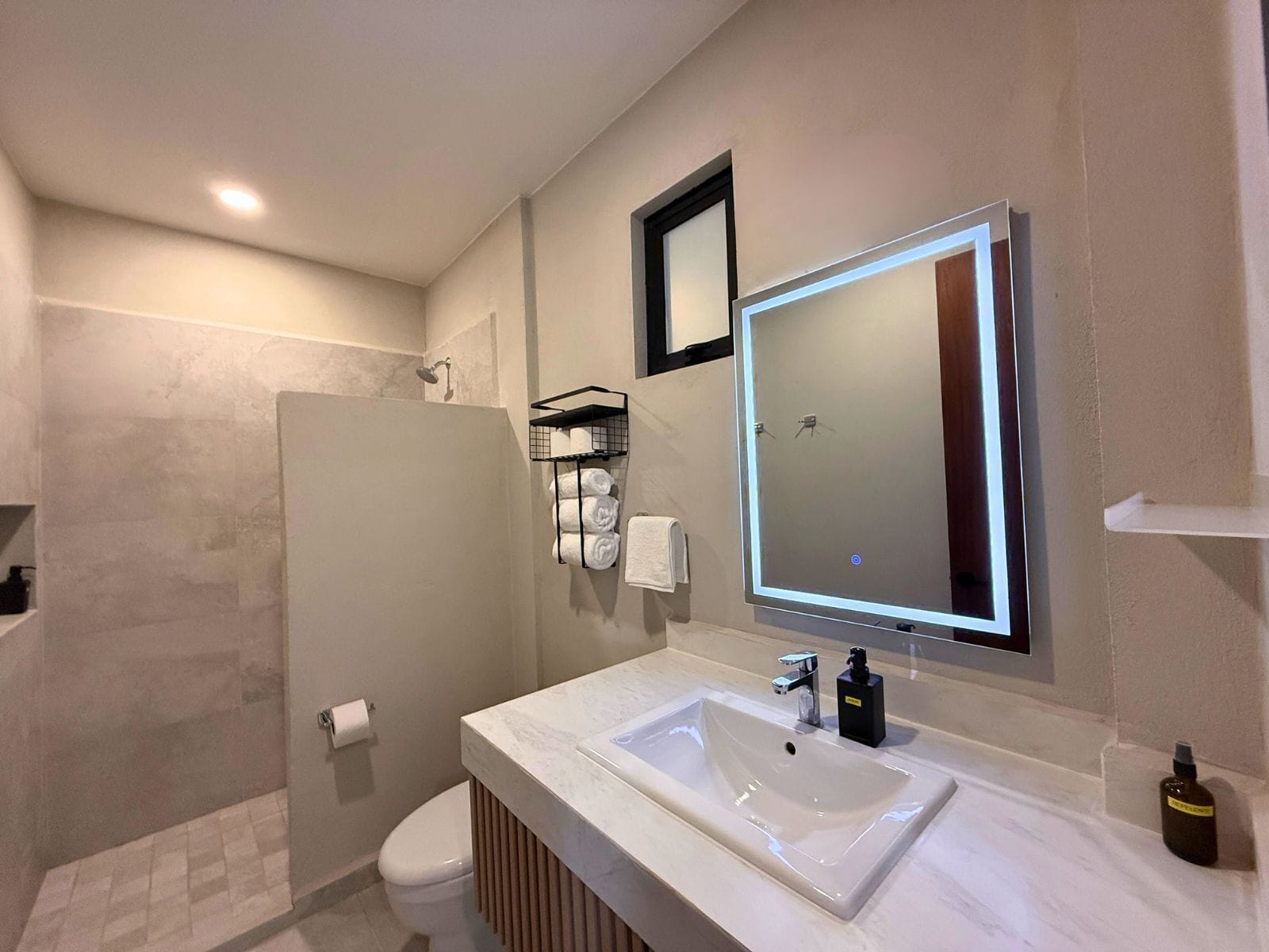 Une salle de bain moderne avec un grand miroir, un lavabo blanc et un espace douche.
