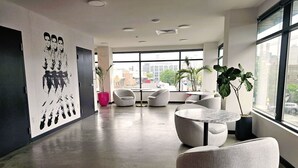 A modern lobby with a large window, seating area, and a wall with a black and white mural.