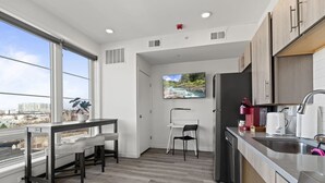 A modern kitchen with a dining area, large windows, and a city view.