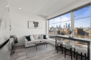 A modern apartment with a large window, a kitchenette, a sofa, and a dining area. - Stylish 1Br King with Gym in the Heart of Old City (Philadelphia)