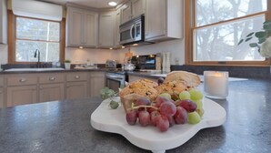 A kitchen with a marble countertop, a white serving board with pastries and grapes, and a lit candle. - Expansive Family Beach Compound @ Ferry Beach ~ Sleeps 17! (Saco)