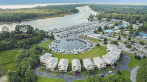 An aerial view of a marina with boats docked, surrounded by residential buildings and lush greenery. - The Captain’s Quarters (New Bern)