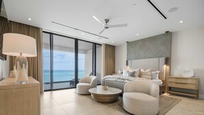 A modern bedroom with a large bed, a ceiling fan, and a view of the ocean. - Aqualina 1001 in Nassau (Nassau)