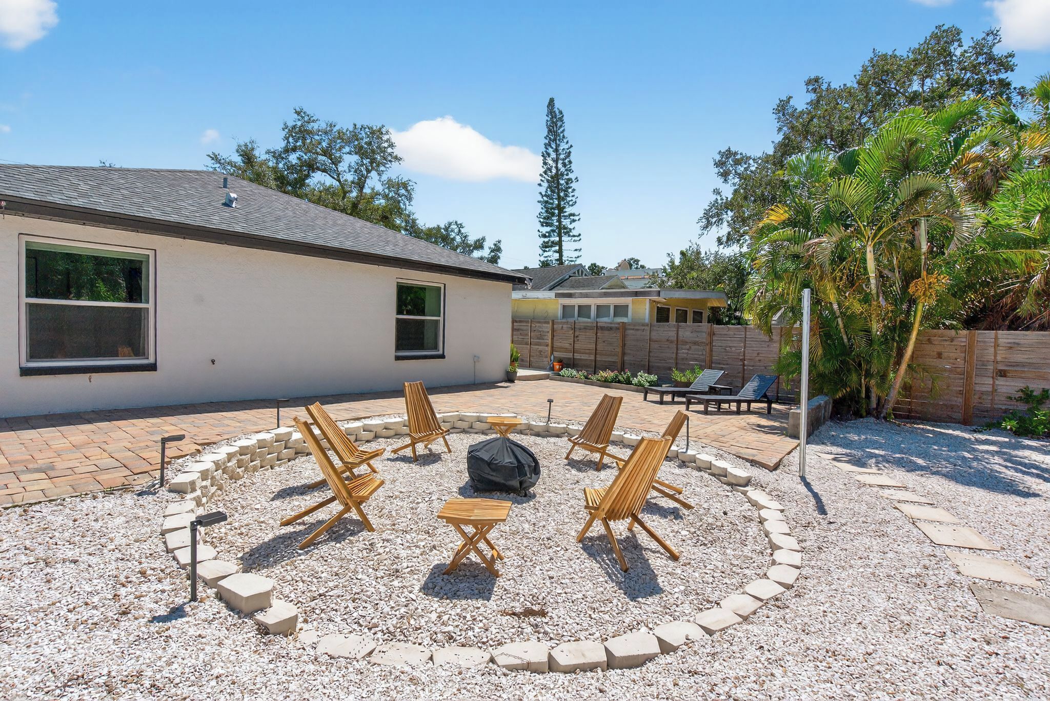 A backyard with a circular seating area, a barbecue grill, and a pool.