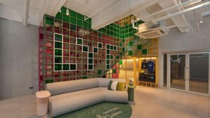 A modern interior with a curved sofa, a small round table, and a green rug with text.