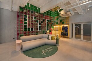 Un intérieur moderne avec un canapé aux lignes courbes, une petite table ronde et un tapis vert orné de motifs textuels.
