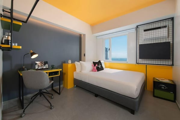 Un dormitorio con cama, escritorio, silla, ventana y televisor.