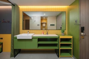 A modern bathroom with a large mirror, a white sink, and green cabinetry.