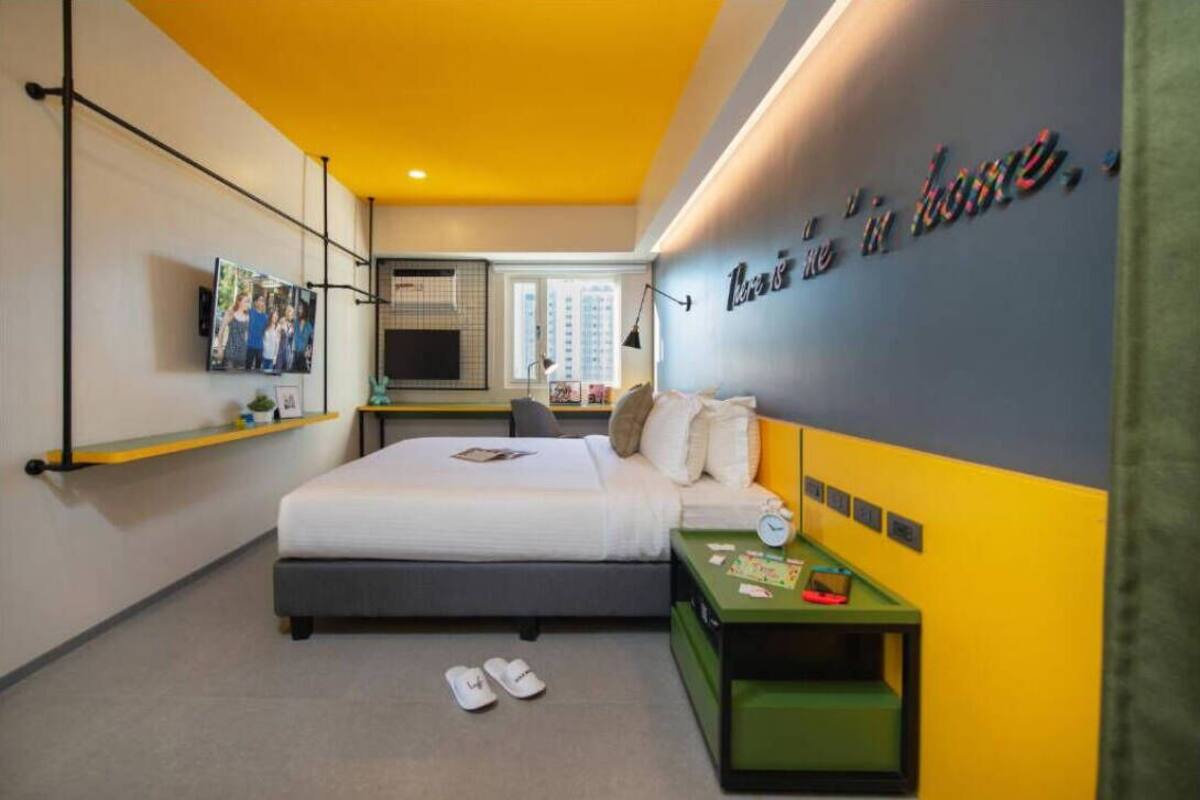 A modern hotel room with a bed, bedside table, and a television mounted on the wall.