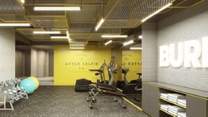A gym with exercise equipment, a yellow wall with text, and a mirrored wall with the word "BUR". - Lyf Malate Manila by Ascott (Manila)