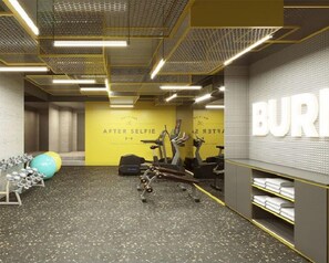 A gym with exercise equipment, a yellow wall with text, and a mirrored wall with the word "BUR".