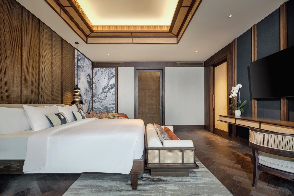 Een moderne slaapkamer met een groot bed, een bank, een televisie en een decoratieve wand.