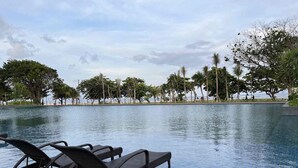 Piscina com espreguiçadeiras e vista para a praia.