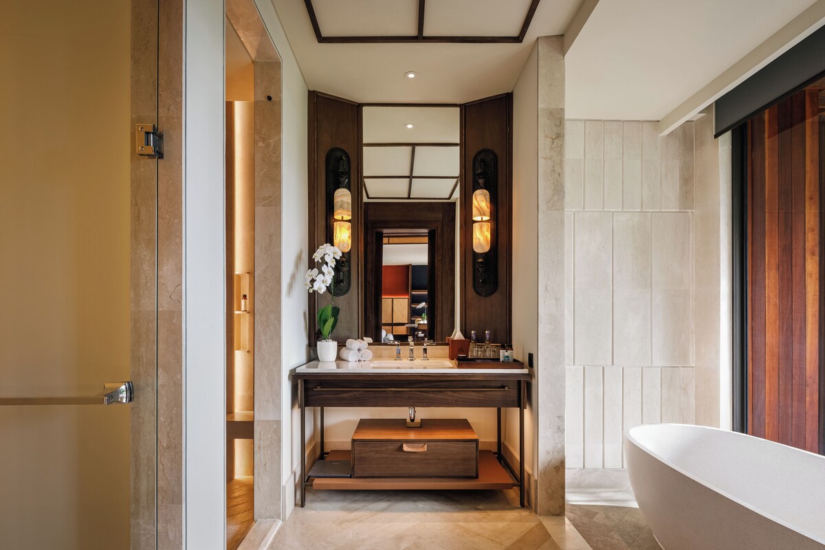 Une salle de bain moderne avec une baignoire sur pieds, un meuble-lavabo avec un miroir et un petit lavabo.