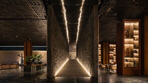 Um interior moderno com uma passarela central, colunas de madeira e iluminação ambiente.