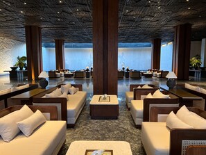 A spacious lobby with multiple seating areas, large pillars, and a view of the sea. - The Meru Sanur (Denpasar)