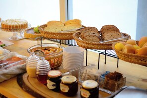 A breakfast buffet with various breads, pastries, and spreads. - Pousada Topazio (Cairu)