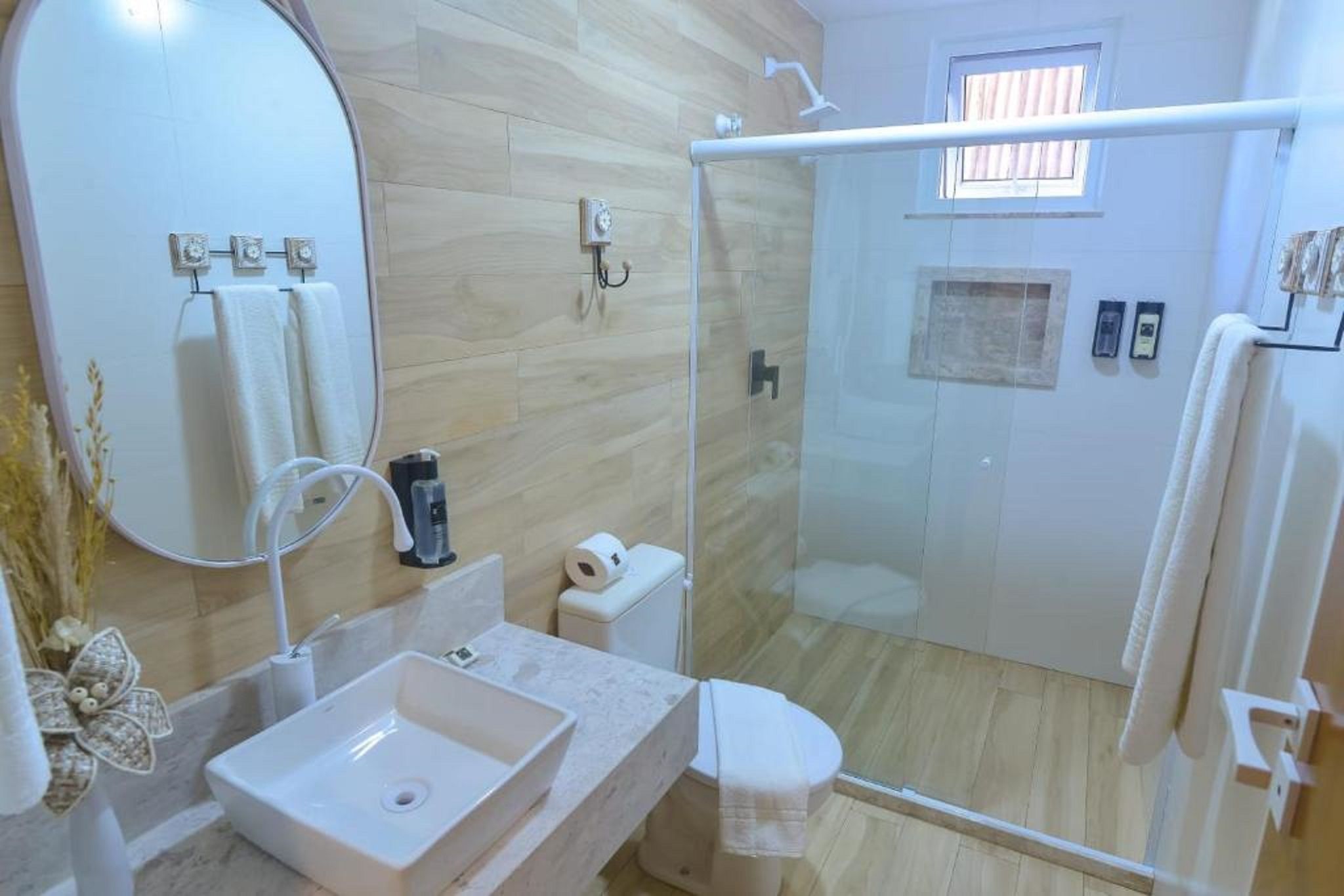 Un baño moderno con ducha de vidrio, un espejo grande y un lavamanos de mármol.