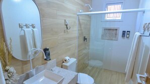 A modern bathroom with a glass-enclosed shower, a large mirror, and a marble sink. - Pousada Topazio (Cairu)