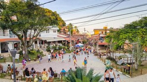 A bustling street scene with pedestrians, outdoor seating areas, and buildings with red-tiled roofs. - Pousada Topazio (Cairu)
