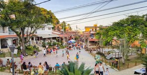 A bustling street scene with pedestrians, outdoor seating areas, and buildings with red-tiled roofs. - Pousada Topazio (Cairu)