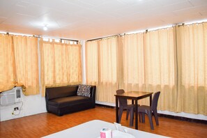 A room with a sofa, a table with chairs, and curtains. - Victoria Mansions By Zuzu (Manila)