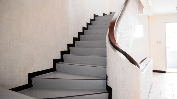 A staircase with a handrail and a textured wall.