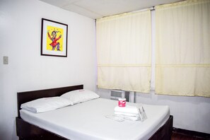 A neatly made bed with white linens, a framed picture on the wall, and a window with yellow curtains. - Victoria Mansions By Zuzu (Manila)