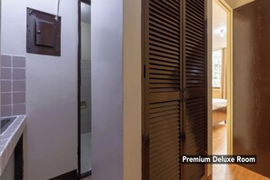 A hallway leading to a room with a sliding door, a tiled wall, and a visible bed in the adjacent room. - Victoria Mansions By Zuzu (Manila)