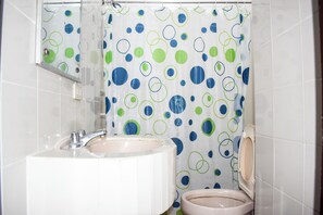 A bathroom with a sink, toilet, and a shower curtain with a polka dot pattern. - Victoria Mansions By Zuzu (Manila)