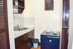 A small kitchen with a sink, cabinets, a blue trash bin, and a coffee maker on a cabinet. - Victoria Mansions By Zuzu (Manila)