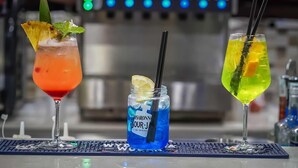 Tres bebidas sobre una barra, con fondo desenfocado.