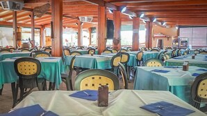 Un amplio comedor interior con varias mesas cubiertas con manteles verdes y sillas con respaldos amarillos.