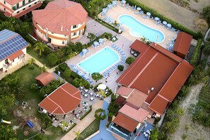 Un complejo turístico con dos piscinas, tumbonas y una zona de juegos para niños.