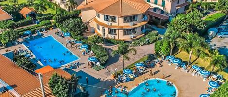 A resort with multiple swimming pools, sun loungers, and palm trees.