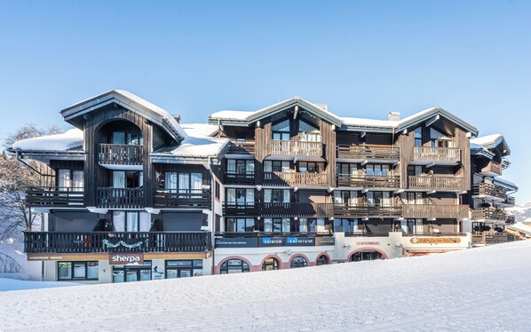 A multi-story ski rental building with balconies and large windows, surrounded by snow. - Residence Le Grand Morillon (Morillon)