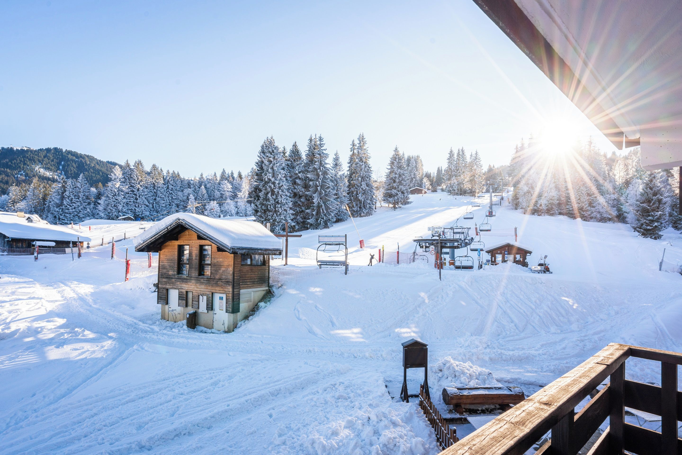 Un centro de esquí cubierto de nieve con una cabaña de madera, telesilla y cielo despejado.