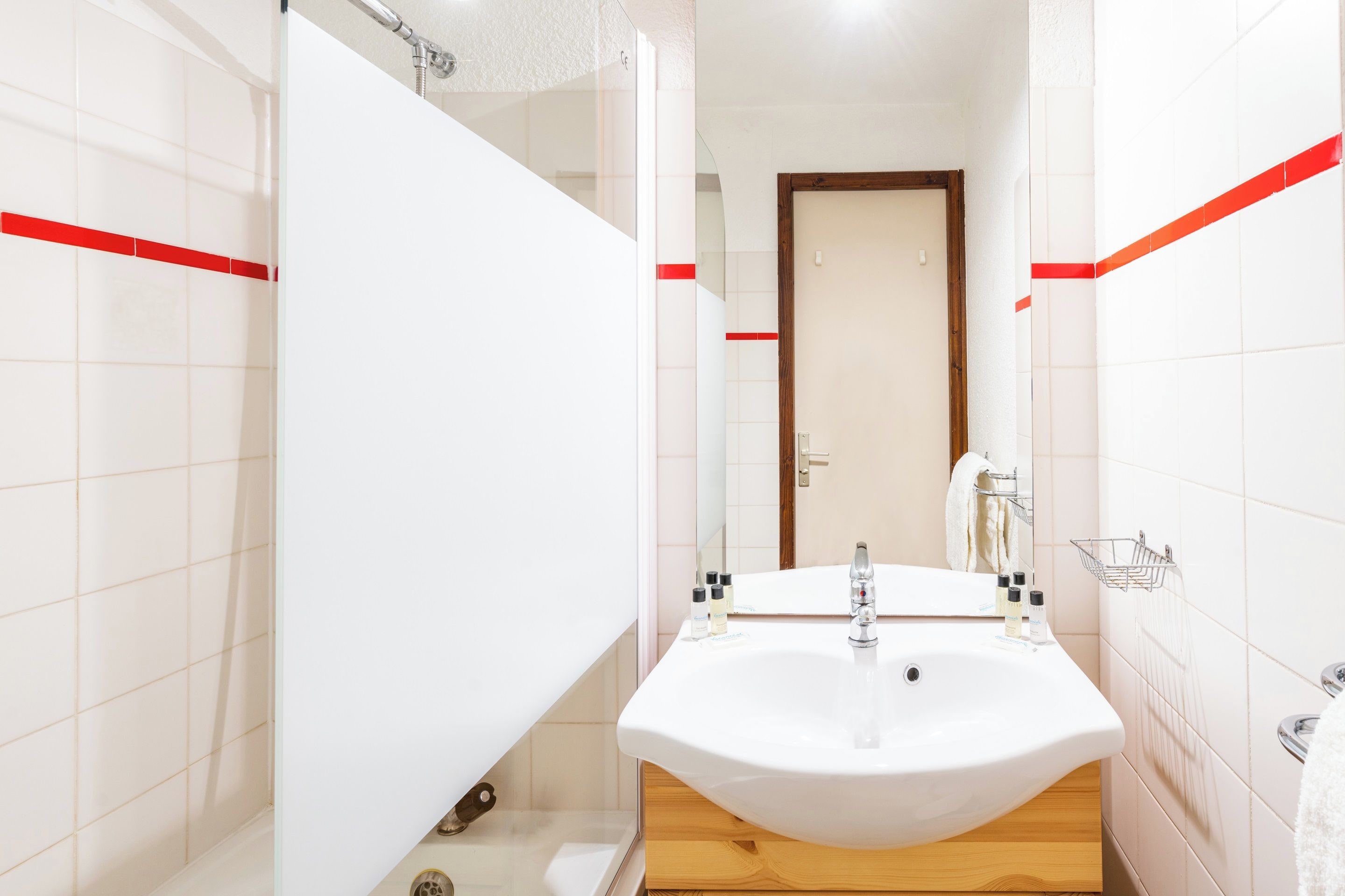 A bathroom with a white sink, wooden vanity, and a towel rack.