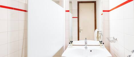 A bathroom with a white sink, wooden vanity, and a towel rack.