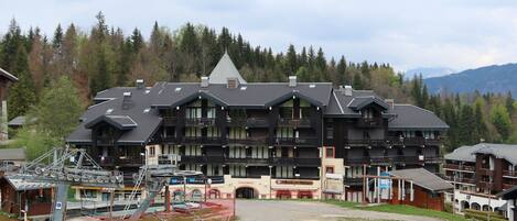 Un grand bâtiment doté de nombreux balcons, avec un télésiège visible au premier plan.