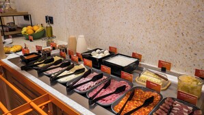 A buffet with various food items and condiments, including meats, cheeses, and fruits.