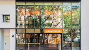A modern hotel with large glass windows, a prominent 'easyHotel' sign, and a visible entrance door.
