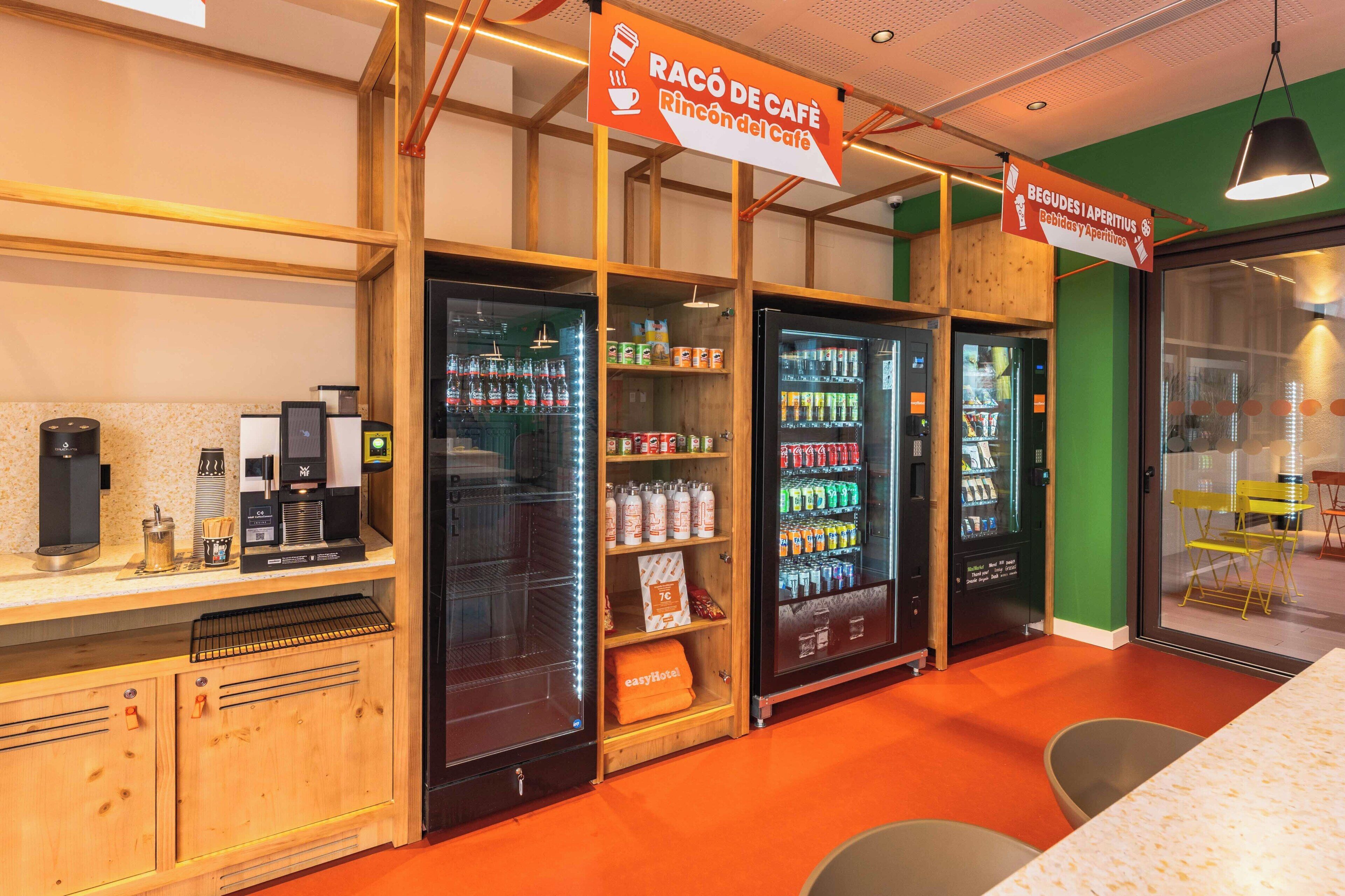 Un café doté de distributeurs automatiques de boissons, d’une machine à café et d’espaces où l’on peut s’asseoir.