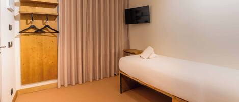 Una habitación de hotel con una cama, un armario de madera, un televisor y una cortina.