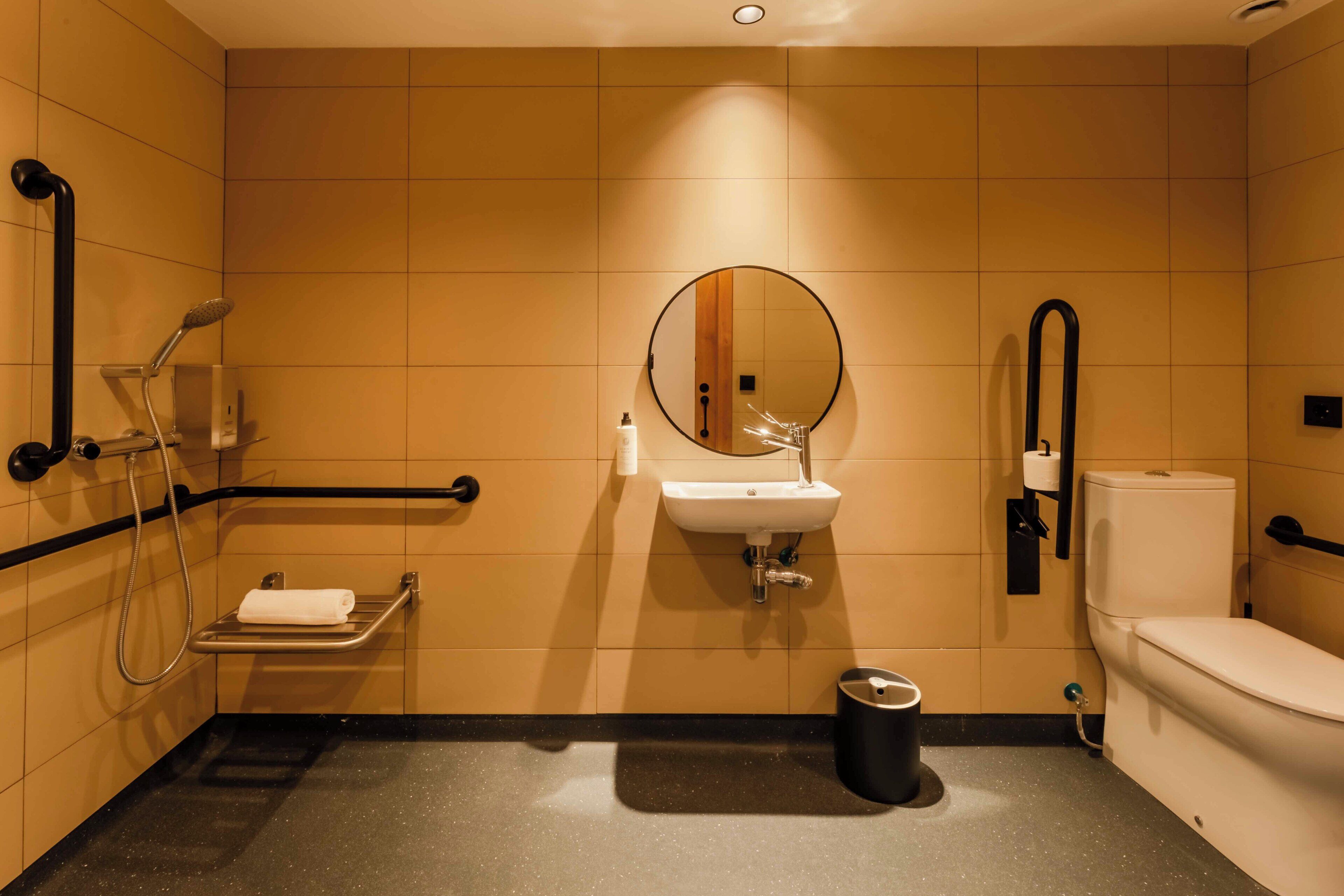 Un baño moderno con lavabo, espejo, inodoro y ducha.