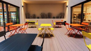 Ein Außenbereich mit Tischen, Stühlen, einer Holzterrasse und einer mit Pflanzen bepflanzten Wand.