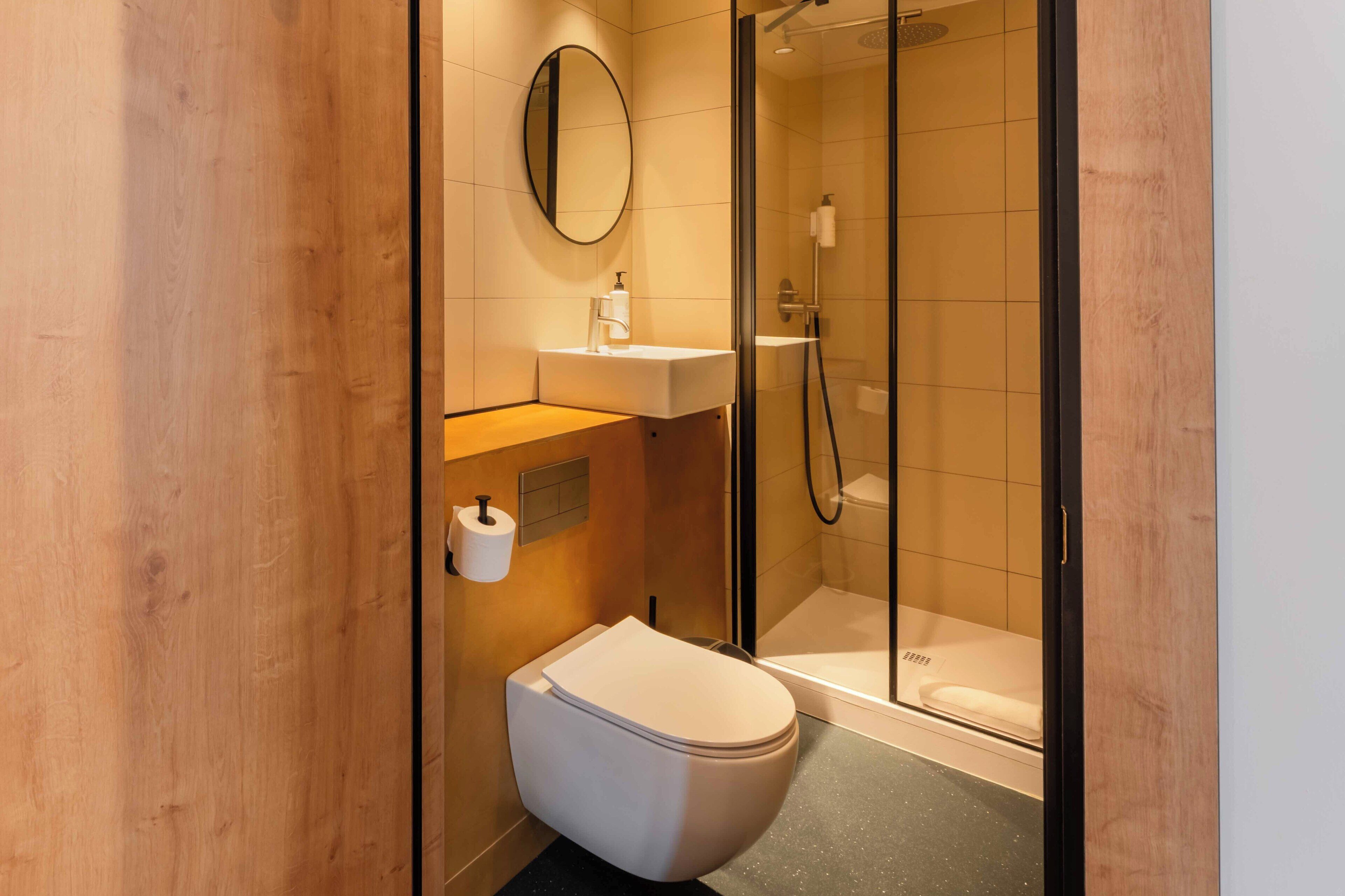 A modern bathroom with a toilet, sink, and glass-enclosed shower.